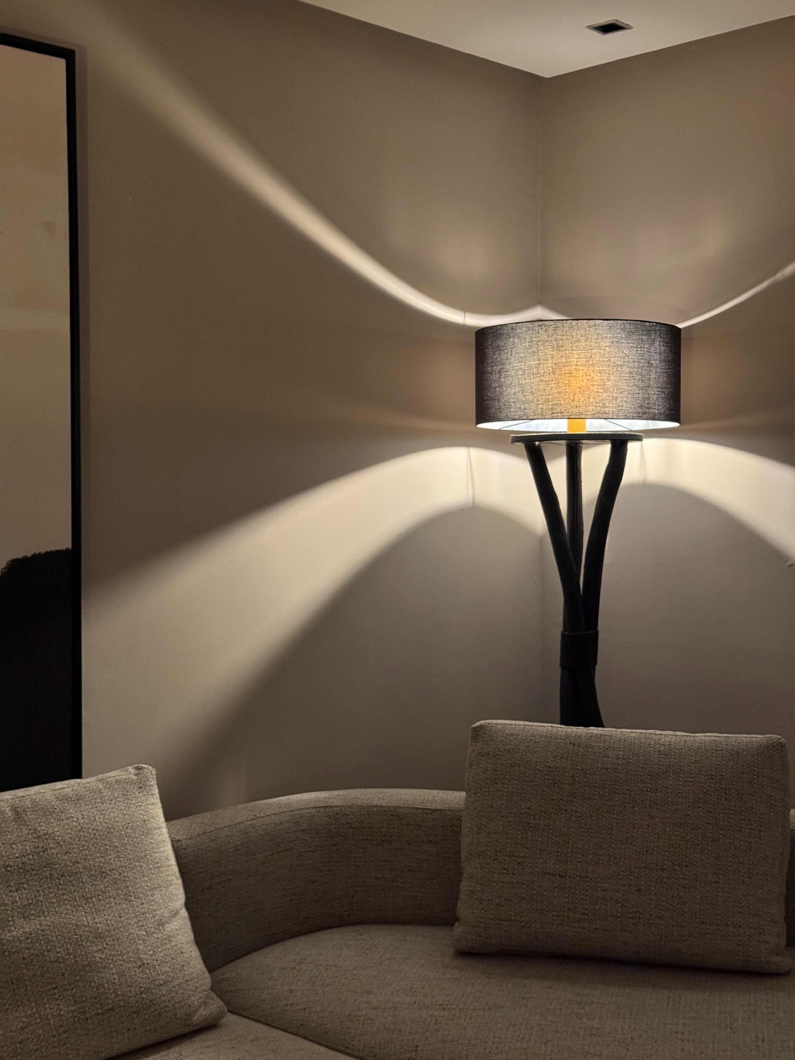 Canapé courbe en tissu clair sous un lampadaire projetant des halos de lumière